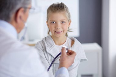 Steteskoplu kız ve doktor kalp atışlarını dinliyor.