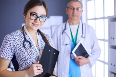 Bir doktor ekibi, kadın ve erkek, ofiste bekliyorlar.