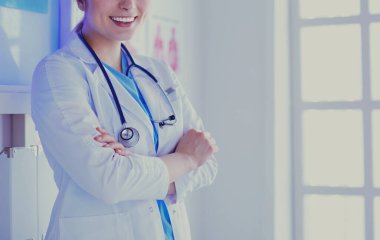 Beyaz üniformalı genç kadın doktor klinikte bekliyor.