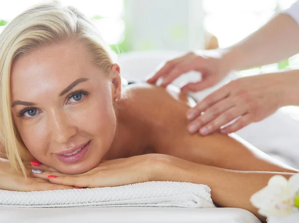 Menina jovem e bonita relaxante no salão de spa. Terapia de massagem durante o verão sazonal ou fundo de primavera — Fotografia de Stock