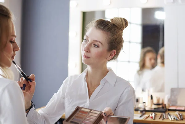 Визажист делает профессиональный макияж молодой женщины — стоковое фото
