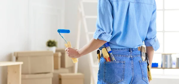 Bella donna sorridente pittura parete interna della casa con rullo di vernice — Foto Stock