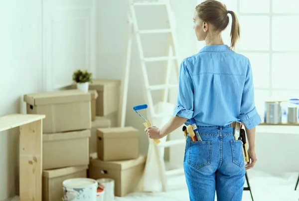 Ganska smilling kvinna målning interiör vägg i hemmet med färg roller — Stockfoto