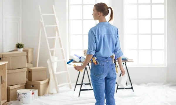 Donna felice dipinge parete con rullo a casa — Foto Stock