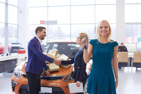 Een man maakt een geschenk - een auto aan zijn vrouw. Ze is hier verbaasd over. Ze zijn erg blij over — Stockfoto