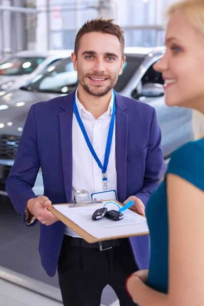 Vendedor de carro vende um carro ao cliente feliz na concessionária de carro e entrega as chaves — Fotografia de Stock
