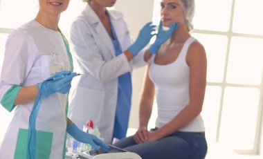 Güzel kadın elinde şırıngayla doktorun yanında duruyor..