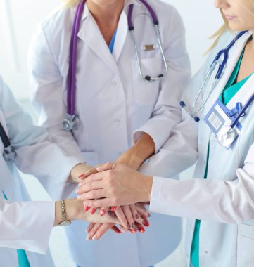 Doktorlar ve hemşireler tıbbi bir ekipte el ele tutuşuyorlar..