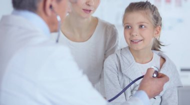 Steteskoplu kız ve doktor kalp atışlarını dinliyor.