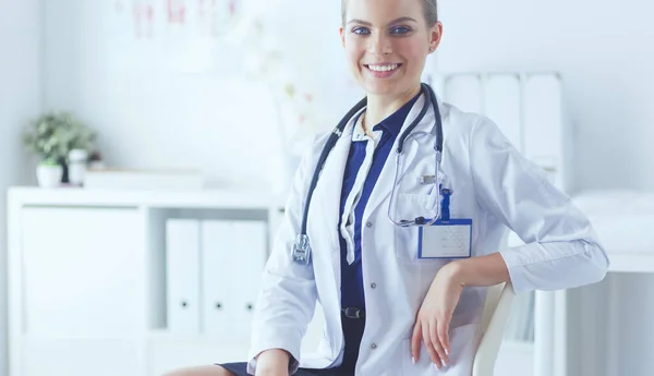 Retrato de uma jovem médica sentada à mesa no hospital — Fotografia de Stock