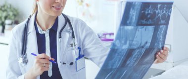 Genç ve çekici bayan doktor röntgen görüntülerine bakıyor.