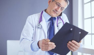 Erkek doktor hastanedeki panoya notlar yazıyor.