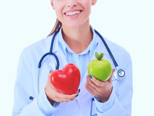 Bonita sorridente médico feminino segurando coração vermelho e maçã verde — Fotografia de Stock