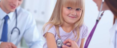 Kadın doktor ameliyatta steteskopla çocuğu muayene ediyor.