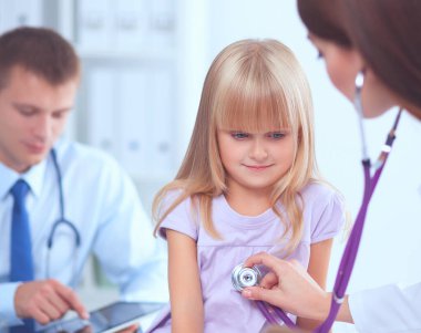 Kadın doktor ameliyatta steteskopla çocuğu muayene ediyor.