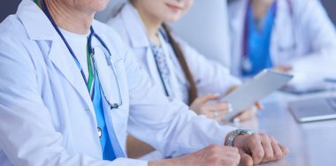 Ciddi bir tıbbi ekip parlak bir ofiste dizüstü bilgisayar kullanıyor.