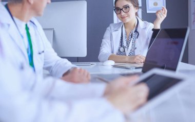 Ciddi bir tıbbi ekip parlak bir ofiste dizüstü bilgisayar kullanıyor.