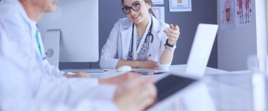 Ciddi bir tıbbi ekip parlak bir ofiste dizüstü bilgisayar kullanıyor.