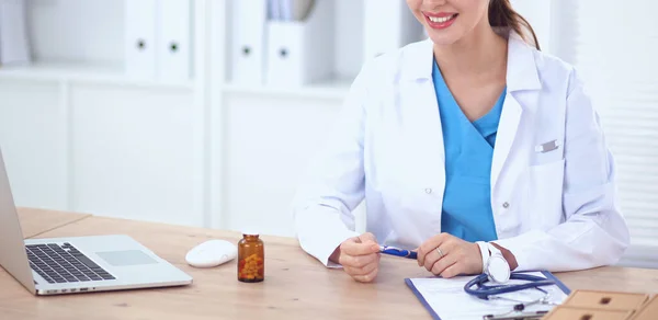 Female doctor sitting on the desk and working a laptop — Stock Photo, Image