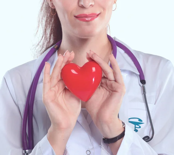 Jeune femme médecin tenant un cœur rouge, debout sur fond gris — Photo