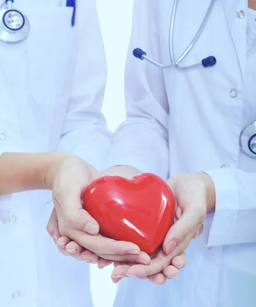 Dos doctora sosteniendo un corazón rojo, aislada sobre fondo blanco —  Fotos de Stock