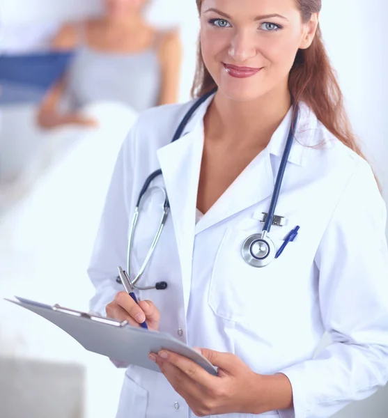 Sorridente medico donna con una cartella in uniforme in piedi in ospedale — Foto Stock