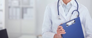 Kadın doktor hastanede dosyayla bekliyor.