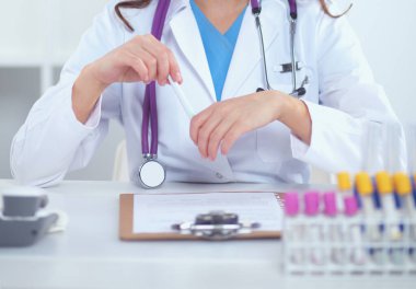 Kadın araştırmacı, beyaz arka planda izole edilmiş ilaç şişeleri ve mataralarla çevrili.