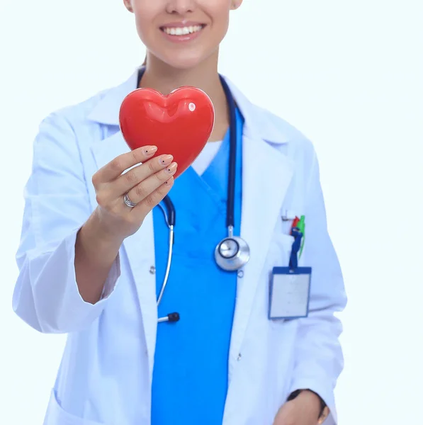 Médica feminina positiva em pé com estetoscópio e símbolo de coração vermelho isolado — Fotografia de Stock