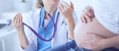 Steteskoplu genç bayan doktor hastanede hamile bir kadınla konuşuyor..