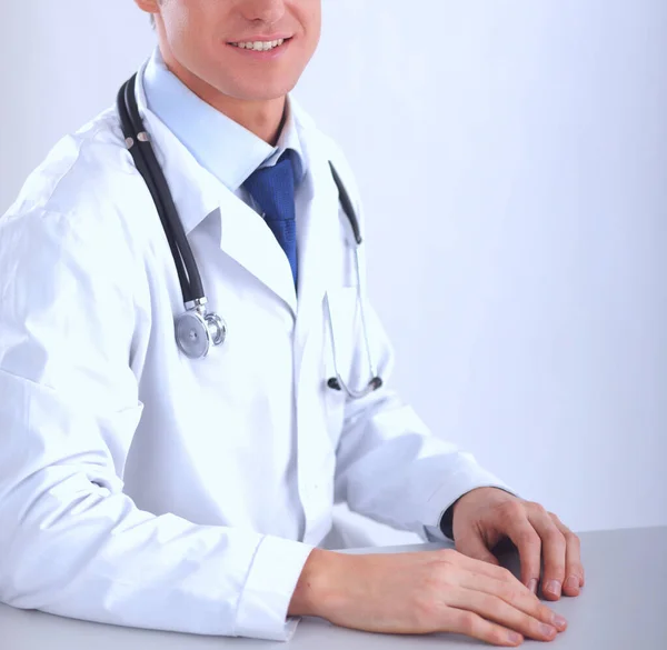 Молодой врач сидит за столом на светлом фоне — стоковое фото