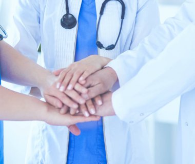 Bir grup doktor ellerini birleştiriyor. Yakın plan.