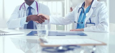 Ofiste tokalaşırken gülümseyen iki genç tıp adamı. Doktorlar. Takım çalışması.