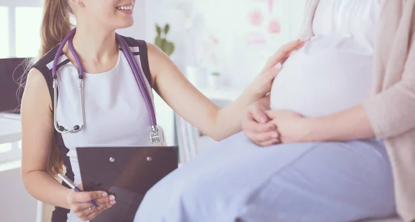 Doctora joven con estetoscopio y tableta que habla con una mujer embarazada en el hospital. — Foto de Stock