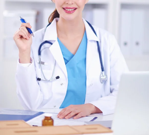 Hermosa joven sonriente médico femenino sentado en el escritorio y w — Foto de Stock