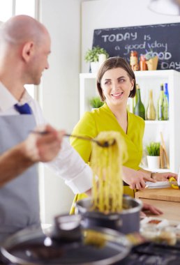 Evdeki mutfakta birlikte yemek pişiren çift.