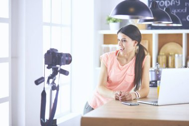 Mutfakta dizüstü bilgisayara benzeyen tariflerle gülümseyen genç bir kadın. Gıda blogcusu kavramı