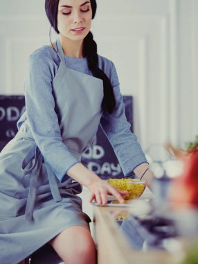 Tablette tarifi takip eden bir kadın evde yemek pişiriyor.