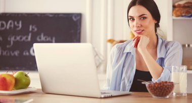 bir fincan kahve ve bir dizüstü bilgisayar mutfakta bir kadınla