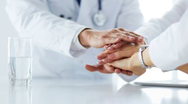 Doktorlar el ele tutuşup yakın çekim yapıyor.