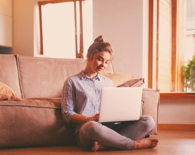oturma odasında yere üstünde laptop ile mutlu bir kadın