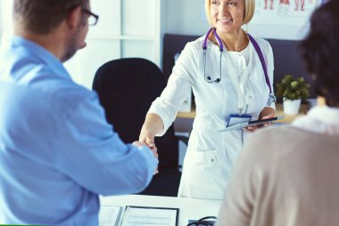 Yaşlı bir çiftle el sıkışan kadın doktor.