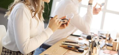 Makyöz, genç bir kadının profesyonel makyajını yapıyor.