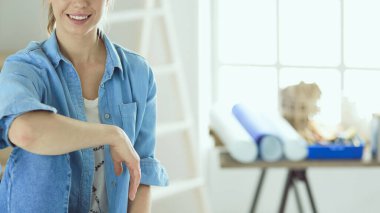 Genç bir kadın evde oturuyor ve tablet bilgisayar kullanarak internetten yeni mobilyalar alıyor.