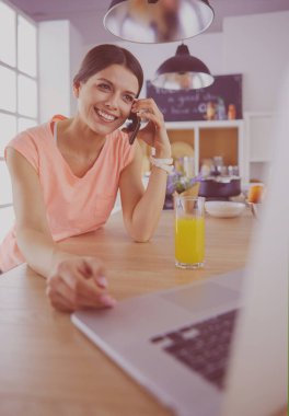 Mutfakta dizüstü bilgisayara benzeyen tariflerle gülümseyen genç bir kadın. Gıda blogcusu kavramı