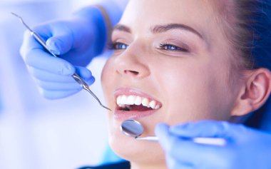 Dişçi muayenehanesinde diş muayenesi yapan ağzı açık genç bir kadın hasta..