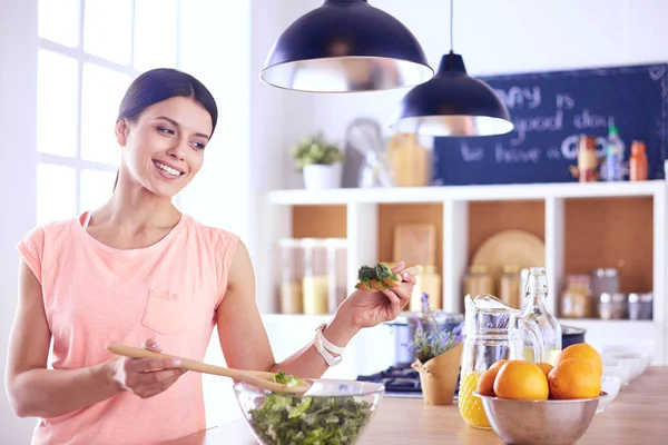 Gülümseyen genç kadın mutfakta taze salata karıştırıyor.. — Stok fotoğraf