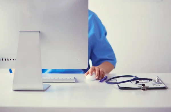 Nieznana kobieta lekarz wypełniając formę medyczną siedząc przy biurku w biurze szpitalnym — Zdjęcie stockowe