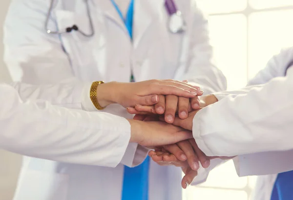 Médicos e enfermeiras a empilhar as mãos. Isolado em branco — Fotografia de Stock