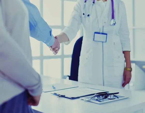 Female doctor handshaking a patients hand and smiling